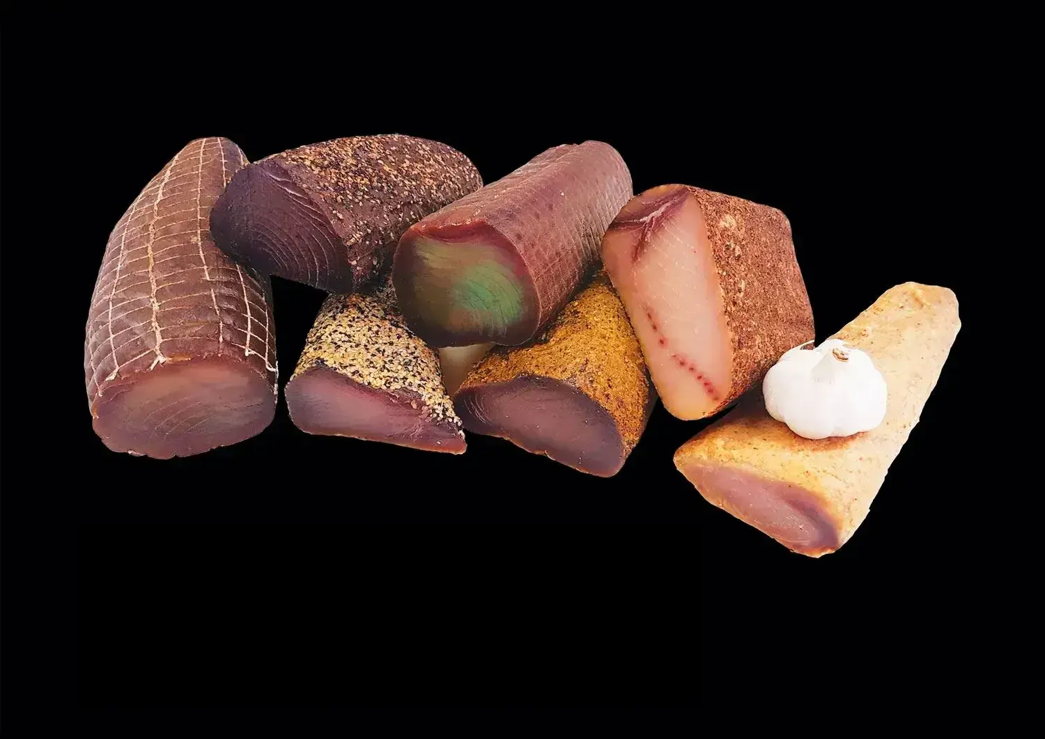 Assortiment de bresaola di tonno, spada affumicato et tonno in porchetta posés sur fond sombre